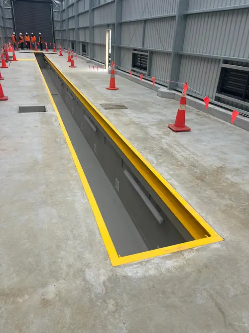 EquipSpecs installation crew standing at the end of a prefabricated steel inspection pit during final checks at NZTA South Auckland.