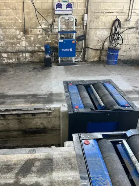 Roller brake tester installed alongside an inspection pit in a New Zealand heavy-vehicle workshop.