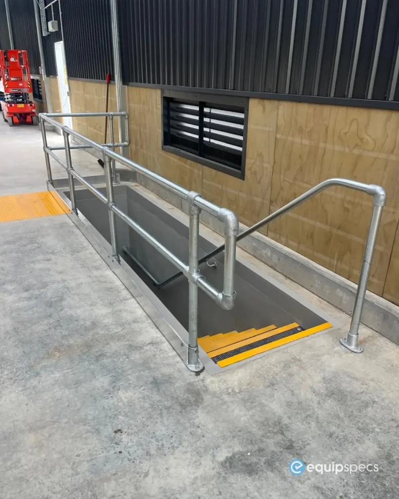 Heavy vehicle inspection pit access stairs and safety handrails installed by EquipSpecs beside a workshop pit ventilation system, designed to support safer technician access and compliance-focused workshop environments.